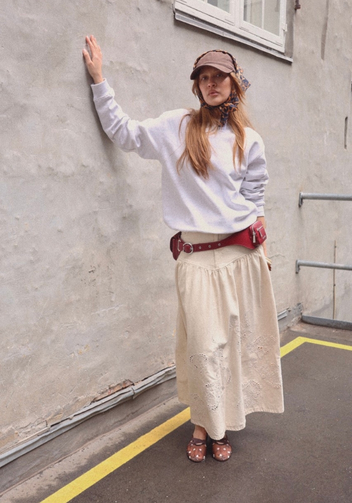 model iført beige nederdel og grå trøje
