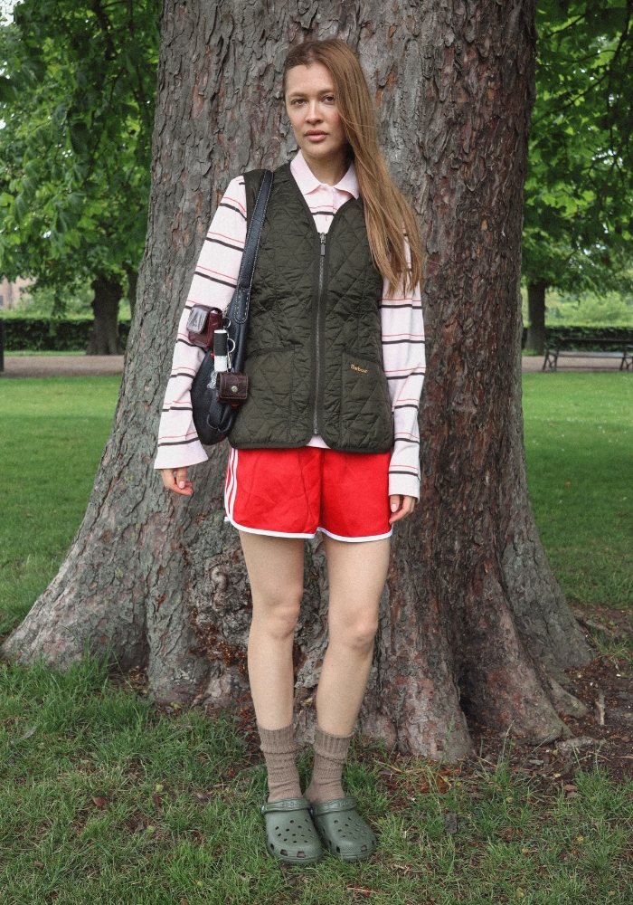 Ung kvinde der står op ad et træ iført festivaloutfit