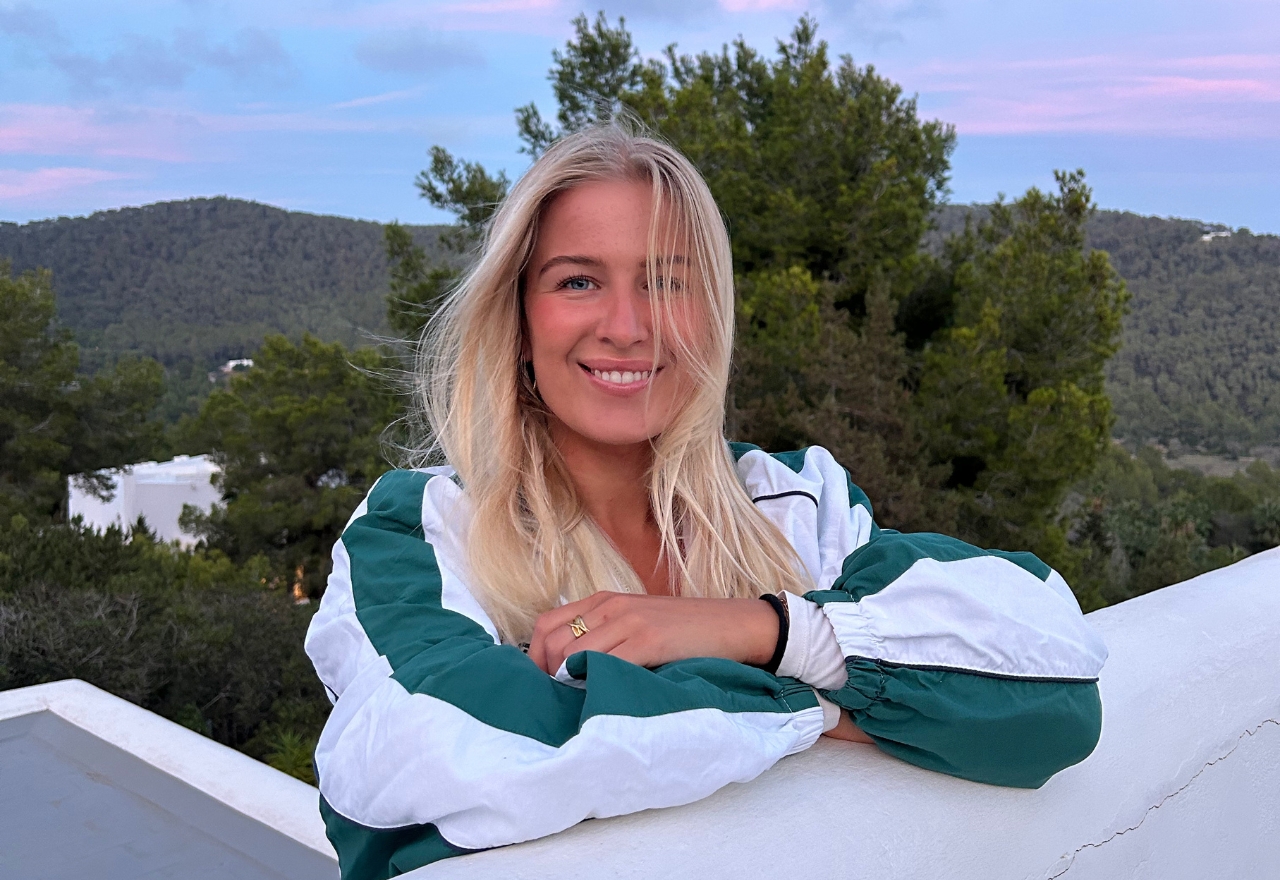 kvinde i grøn jakke står ved mur