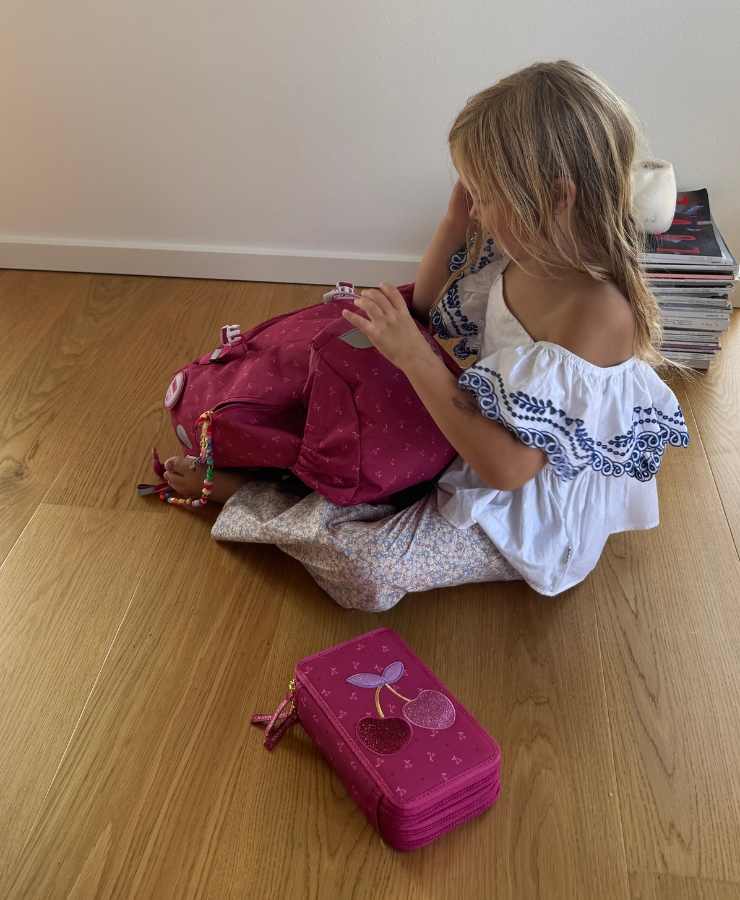 barn sidder på gulv og åbner skoletaske