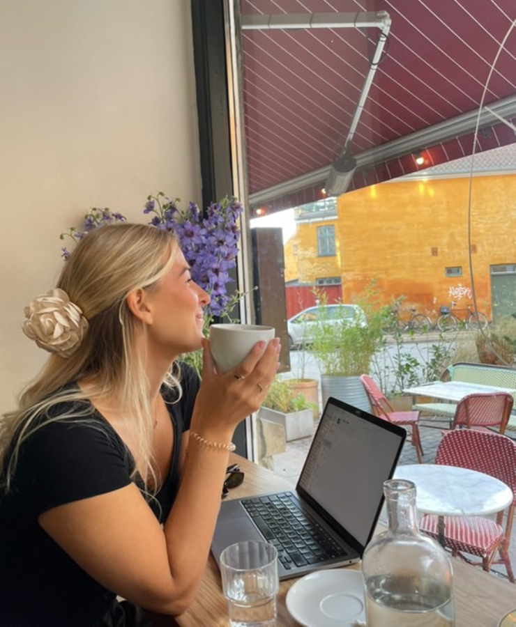 Kvinde sidder på cafe med en kop kaffe i hånden